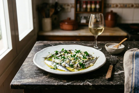 Boquerones en vinagre servidos con ajo y perejil sobre plato blanco