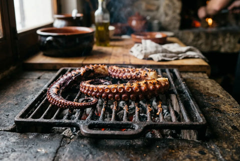 Tentáculos de pulpo marcándose sobre parrilla de brasa con las ventosas hacia abajo