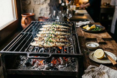 Sardinas alineadas sobre una parrilla de hierro con brasas debajo